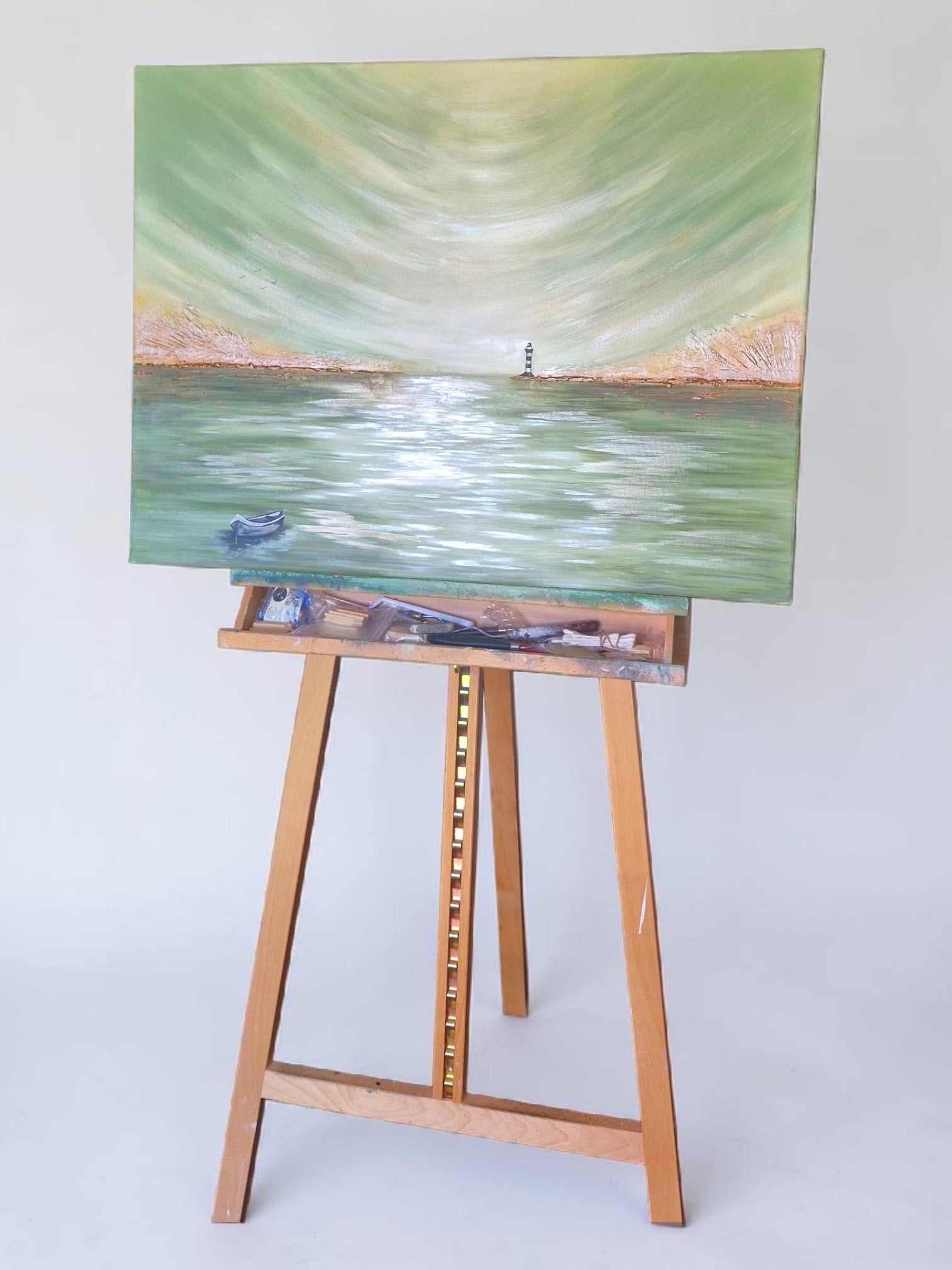 Painting of a lighthouse on a lake with a wooden easel on a white background