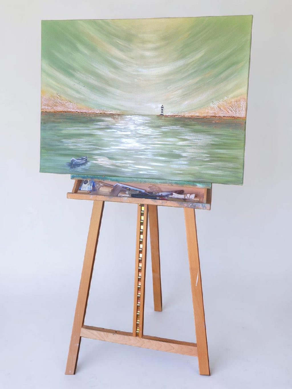 Painting of a lighthouse on a lake with a wooden easel on a white background