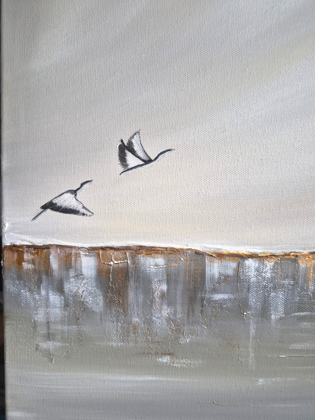 An abstract landscape painting featuring two flying black and white birds against a textured light gray and beige sky, with a horizontal band of brown and gray brushstrokes resembling a shoreline or horizon.