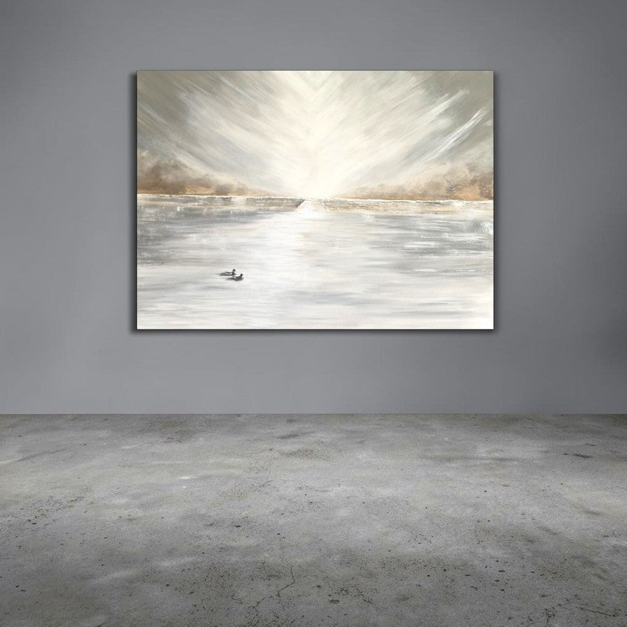 A horizontal canvas wall art print depicting an abstract snowy or icy landscape with a bright sunburst, hanging on a gray wall above a concrete floor.