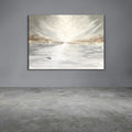 A horizontal canvas wall art print depicting an abstract snowy or icy landscape with a bright sunburst, hanging on a gray wall above a concrete floor.